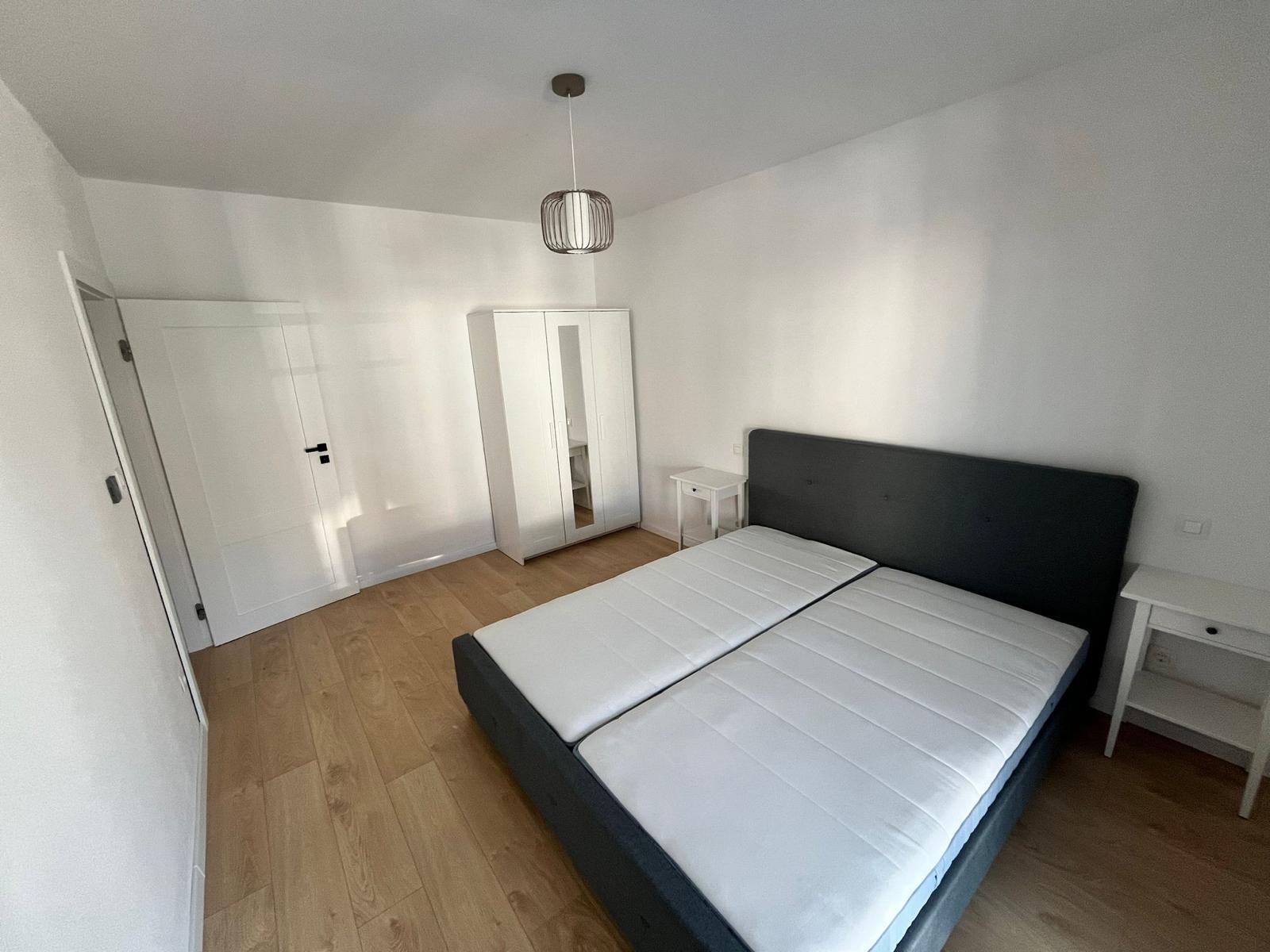 Spálňa s bielou skriňou a novou manželskou postelou v apartmáne