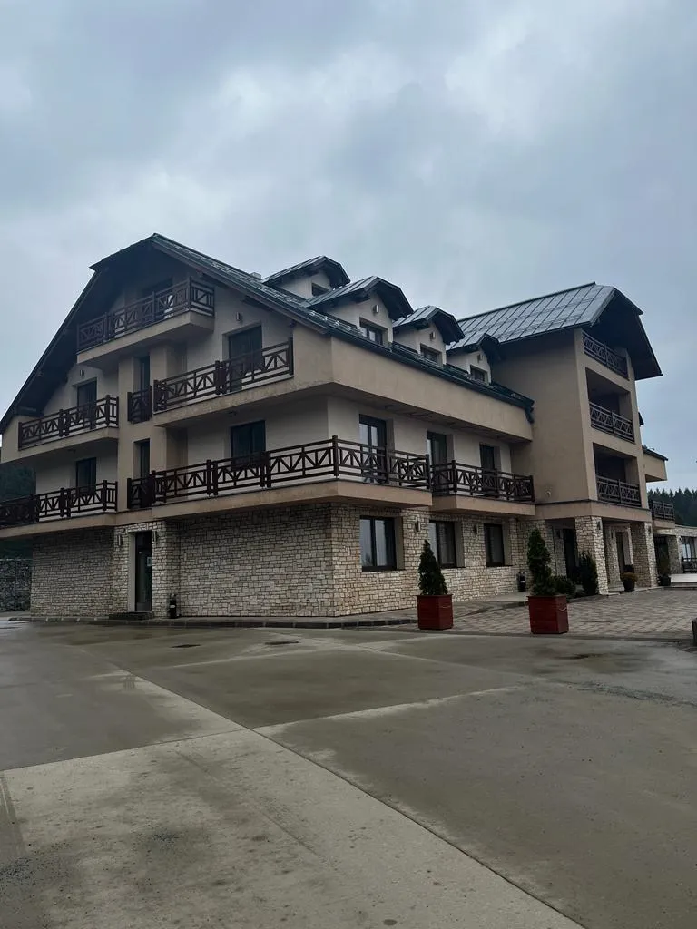 Hotel s kamennou fasádou, drevenými balkónmi a tmavou strechou