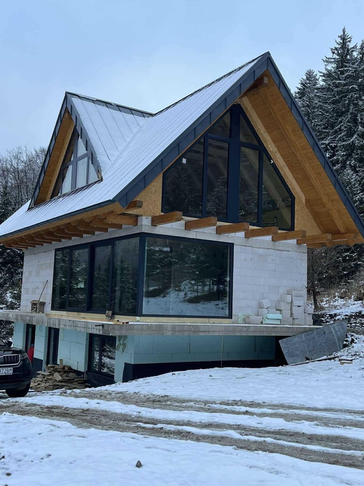 Hotová rekreačná chata na Kubínskej Holi s plechovou strechou a veľkými oknami v zime