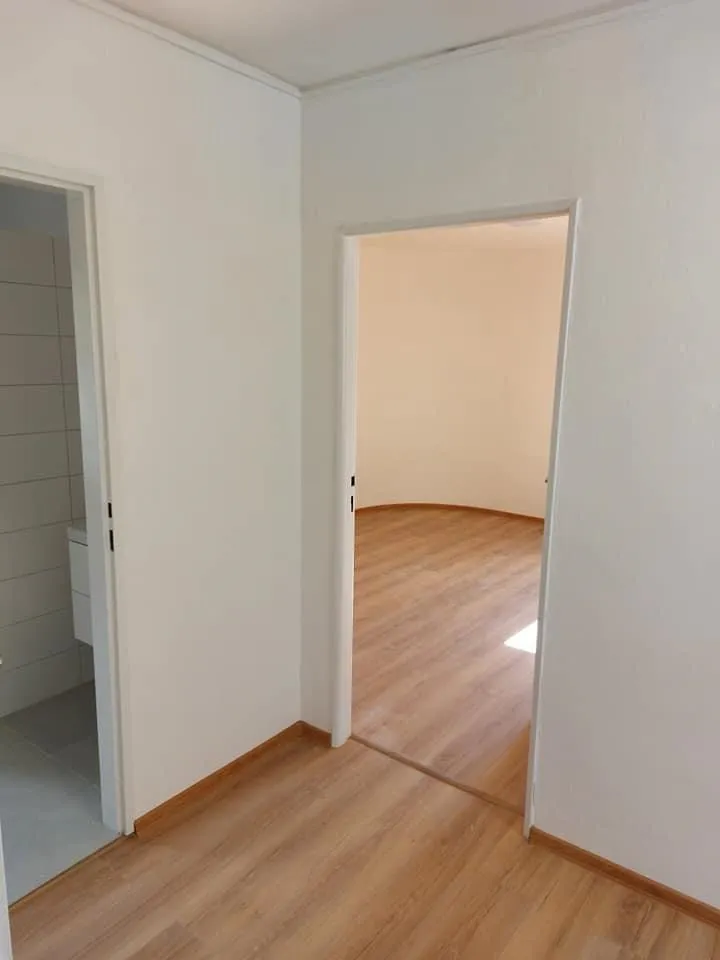 Chodba s bielymi dverami a laminátovou podlahou po rekonštrukcii